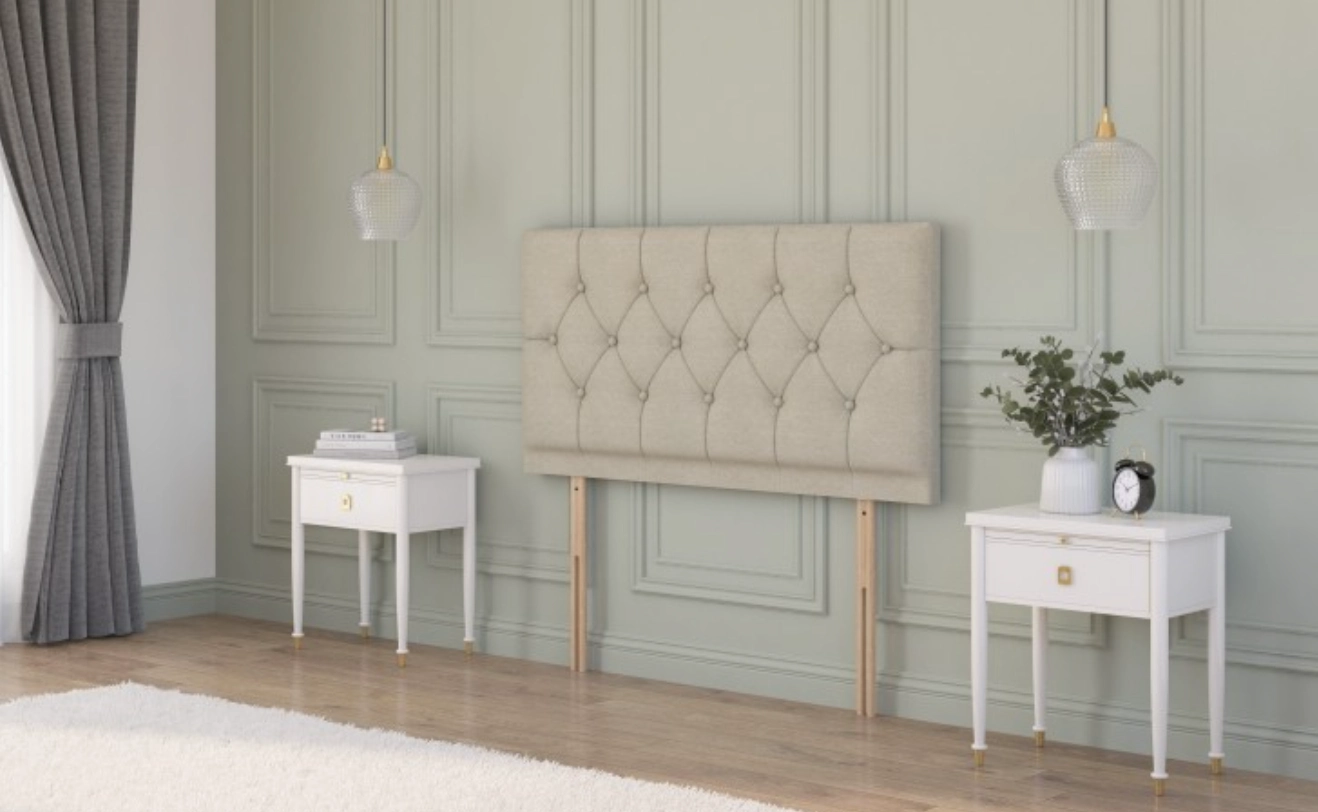  Beige plush velvet strutted headboard with a chesterfield design in a rustic cottage bedroom between two bedside tables.